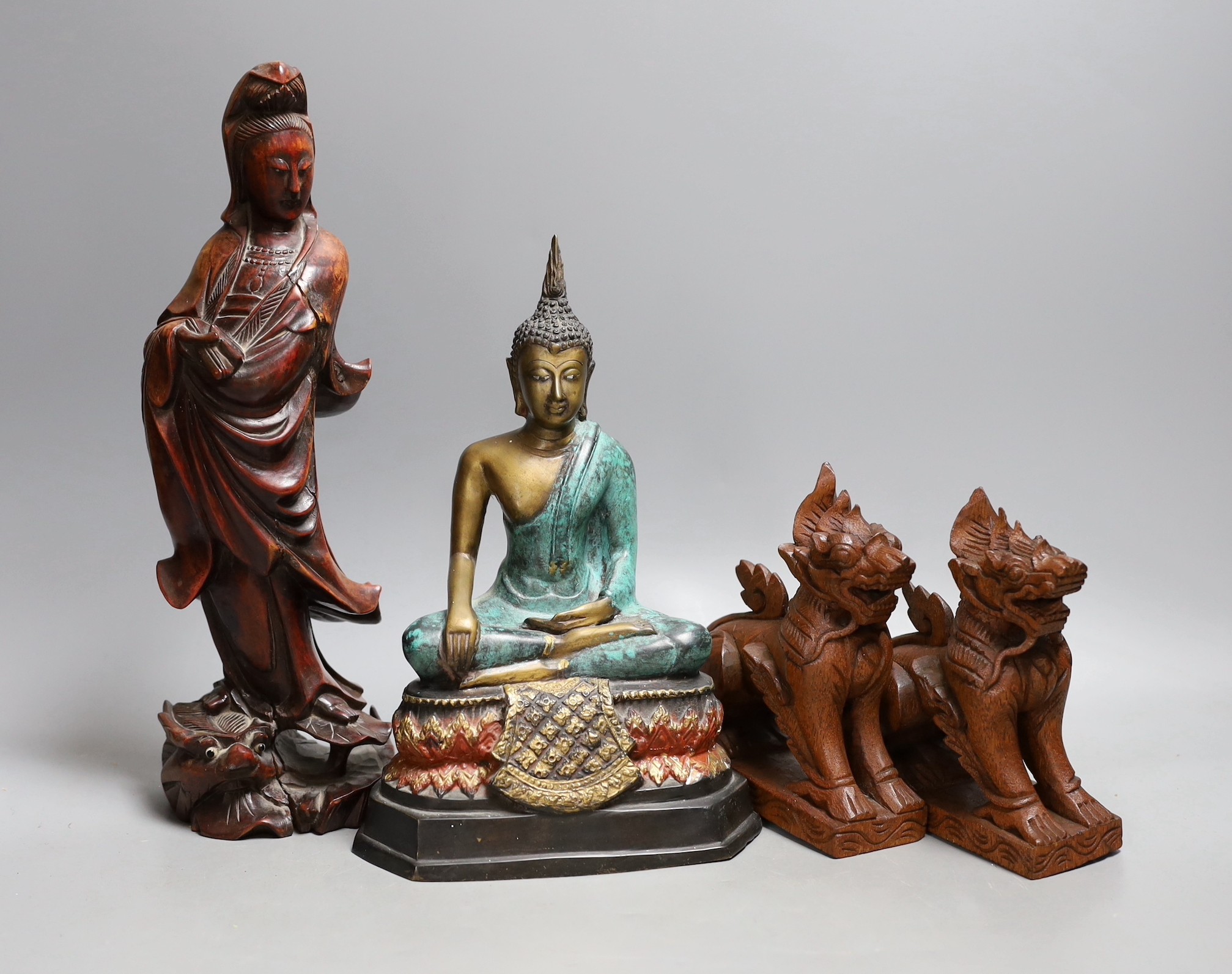 A Chinese carved wood figure of Guanyin, a pair of Buddhist lions and a cast brass figure of Buddha, tallest 30cm